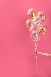 Woman holding bunch of balloons on color background, closeup