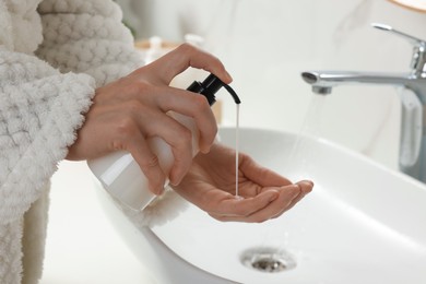 Photo of Woman using liquid soap dispenser in bathroom, closeup