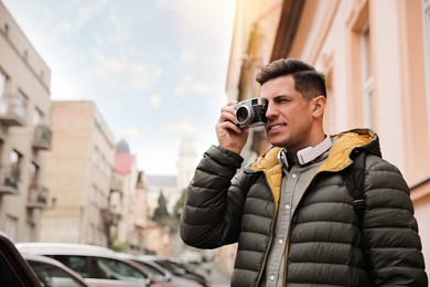 Tourist with camera taking photos on city street