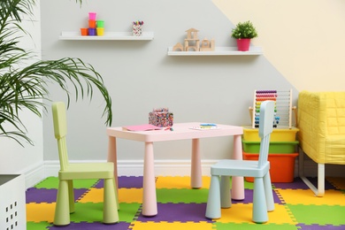 Photo of Stylish playroom interior with table, chairs and sofa