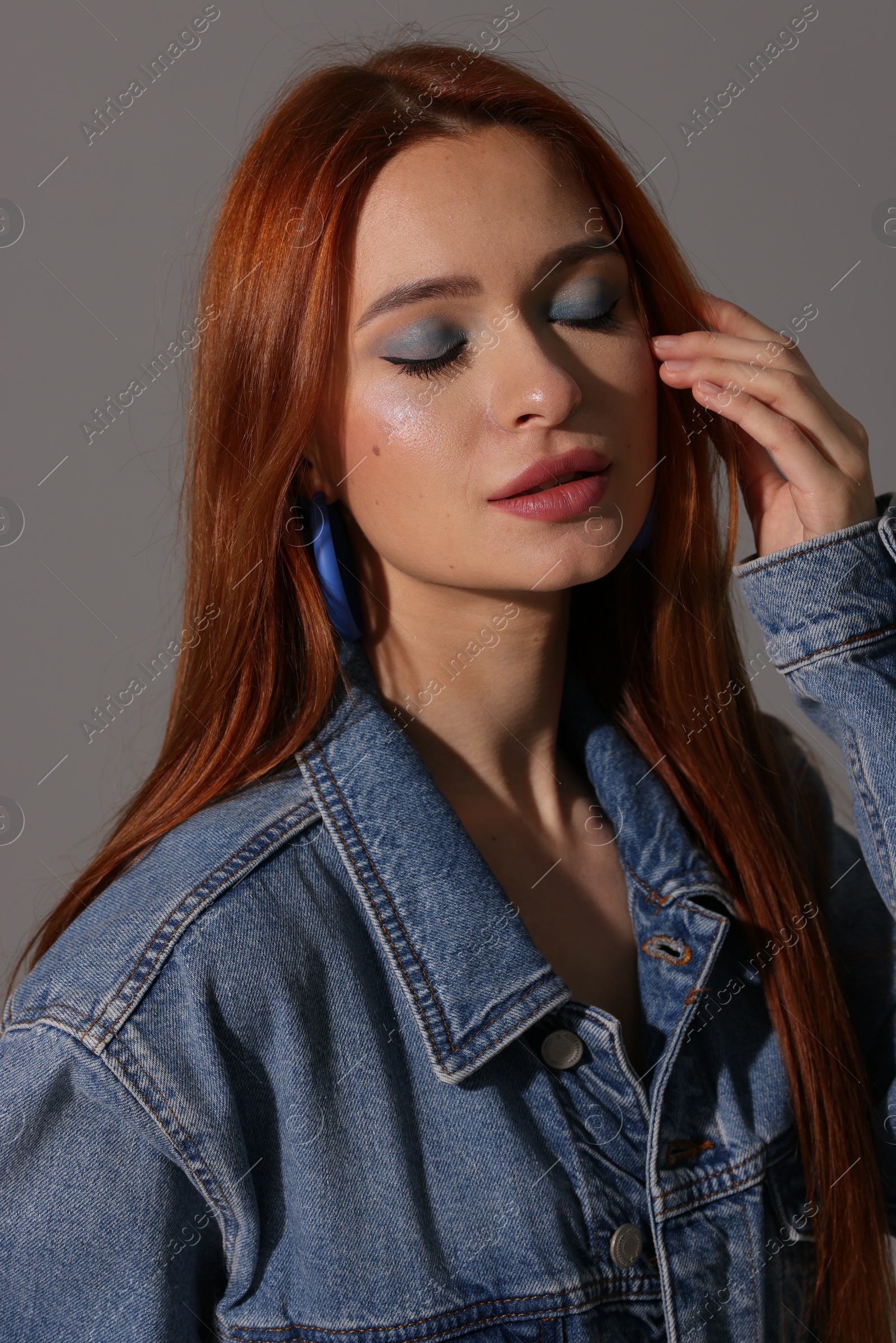 Photo of Beautiful young woman in denim jacket on gray background