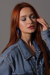 Photo of Beautiful young woman in denim jacket on gray background