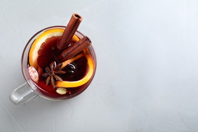 Photo of Glass cup of tasty mulled wine on grey background, top view. Space for text