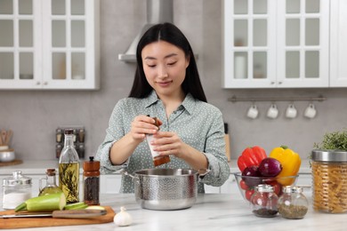 Beautiful woman cooking at countertop in kitchen