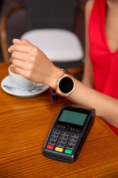 Photo of Woman making payment with smart watch in cafe, closeup