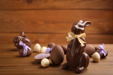 Photo of Chocolate Easter bunny and eggs on wooden table. Space for text