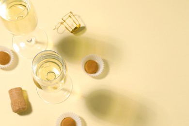 Photo of Glassesdelicious sparkling wine and chocolate truffles on light yellow background, above view. Space for text