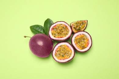 Photo of Fresh ripe passion fruits (maracuyas) with leaves on light green background, flat lay