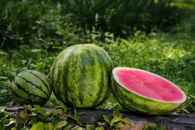 Different delicious ripe watermelons on stone surface outdoors