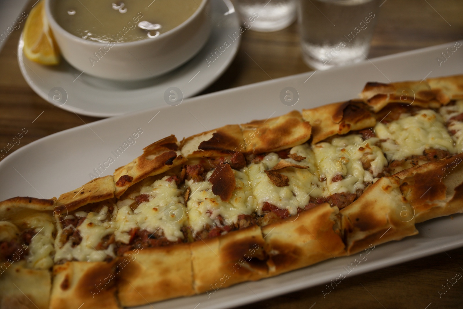 Photo of Delicious pide on wooden table, closeup. Traditional Turkish street food