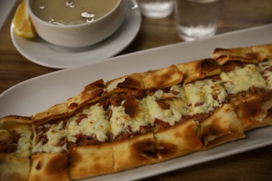 Delicious pide on wooden table, closeup. Traditional Turkish street food