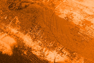 Image of Strokes of orange acrylic paint on canvas, closeup