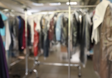 Photo of Blurred view of racks with clothes in dry-cleaning
