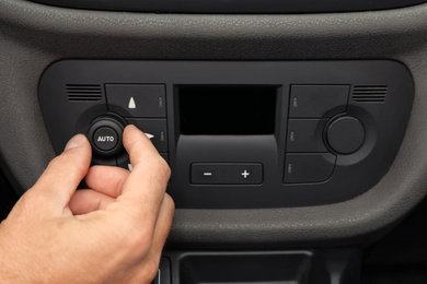 Photo of Man adjusting air conditioner in car, closeup