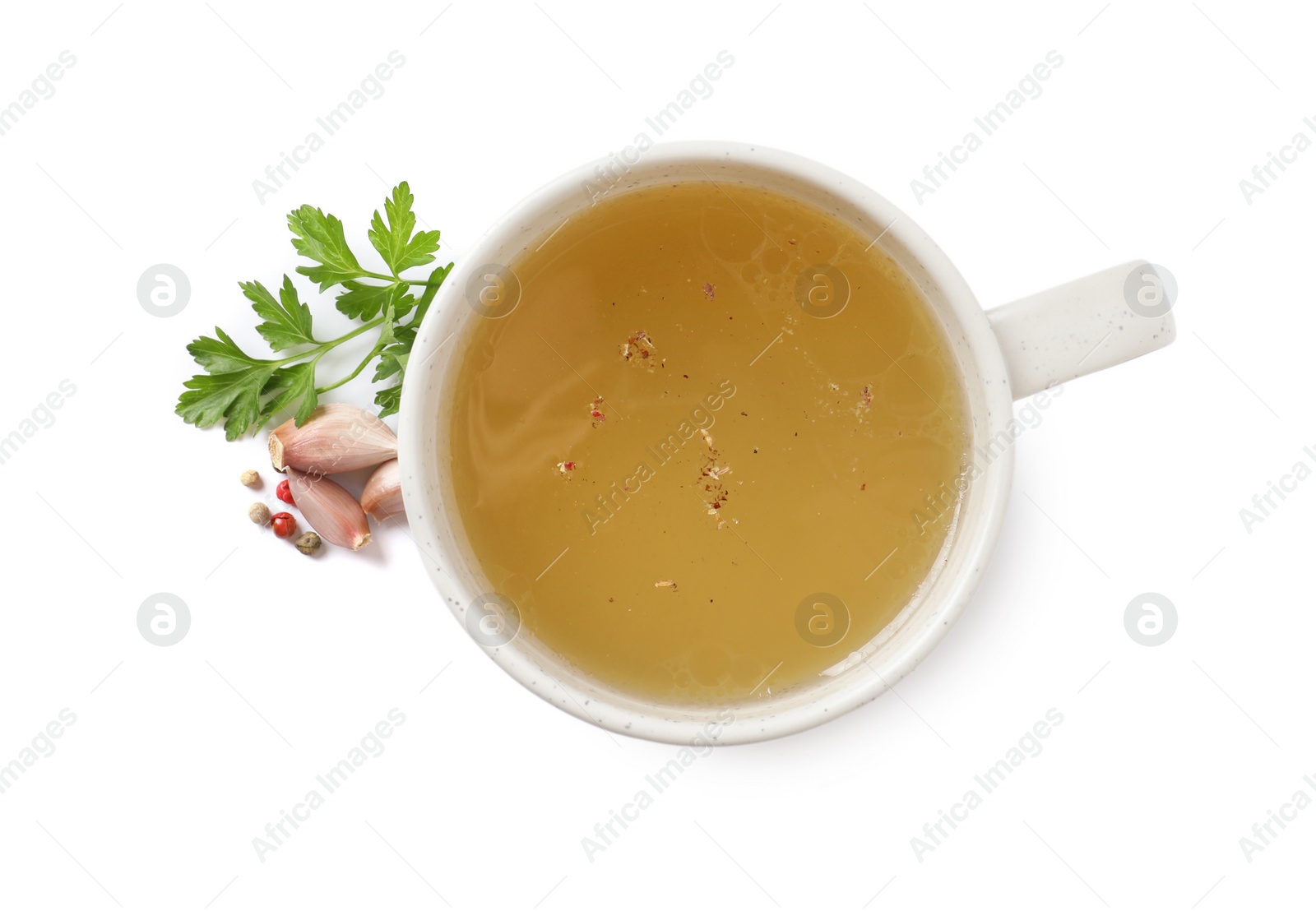 Photo of Hot delicious bouillon in cup and ingredients on white background, top view