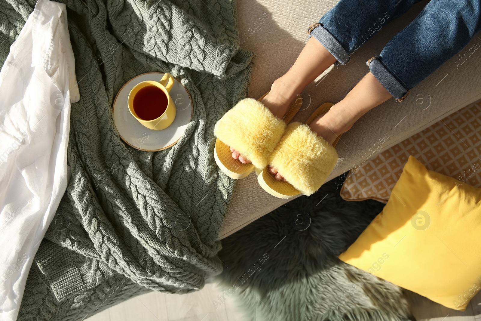 Photo of Woman with cup of tea wearing soft comfortable slippers at home, top view