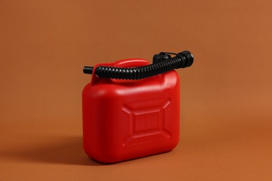 Photo of New red plastic canister on brown background