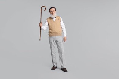 Senior man with walking cane on light gray background