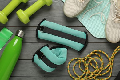 Photo of Turquoise weighting agents and sport equipment on grey wooden table, flat lay