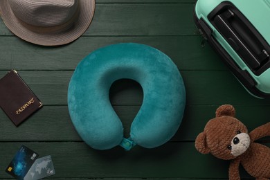 Flat lay composition with turquoise travel pillow on green wooden background