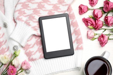 Photo of E-book reader cardigan, flowers and cup of tea on white wooden table, flat lay. Space for text