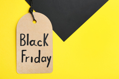 Photo of Tag with words BLACK FRIDAY on color background, top view. Space for text