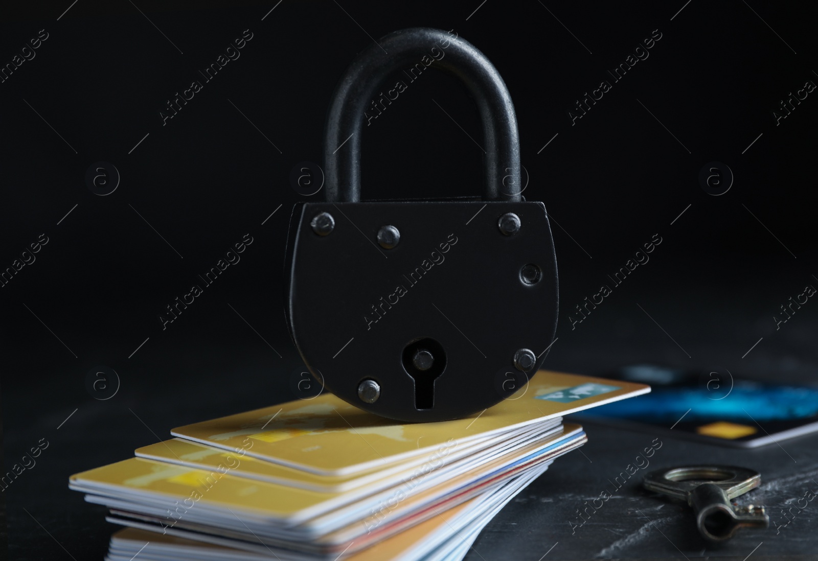 Photo of Credit cards, padlock and key on black slate table. Protection from cyber attack