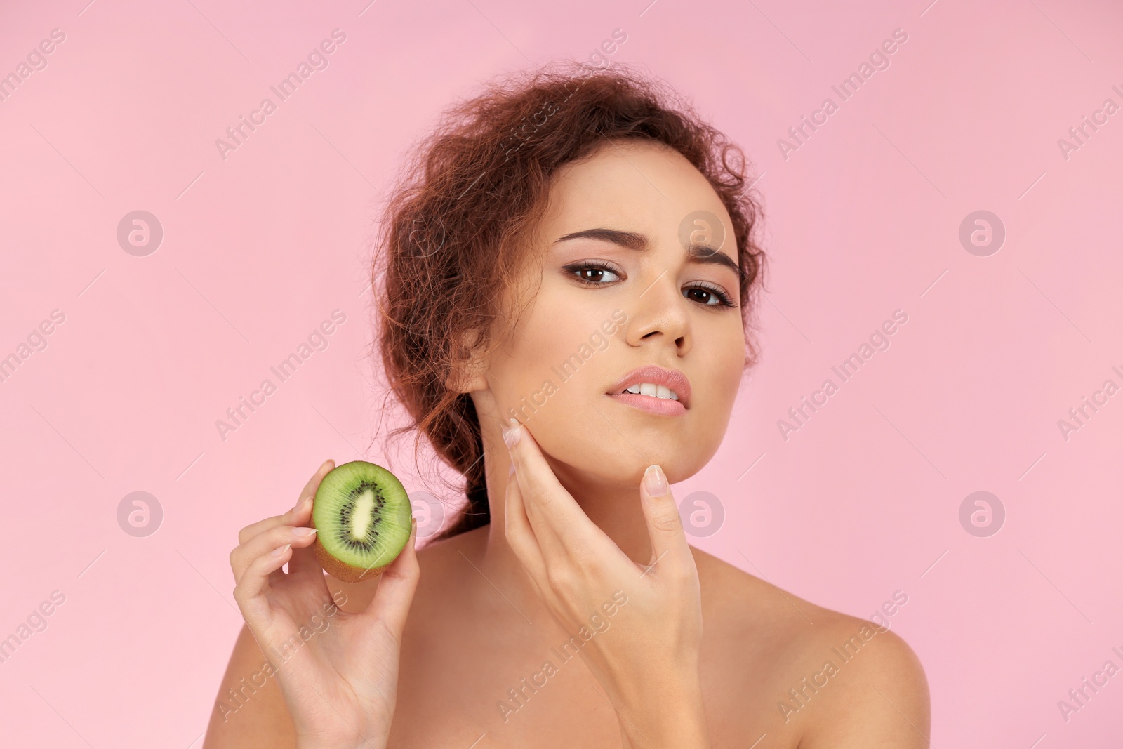 Photo of Beautiful young woman with acne problem holding kiwi on color background. Skin allergy