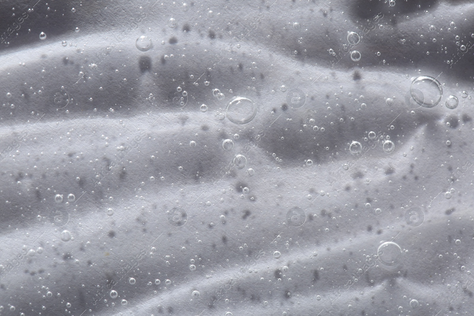 Photo of Clear cosmetic serum on light background, macro view