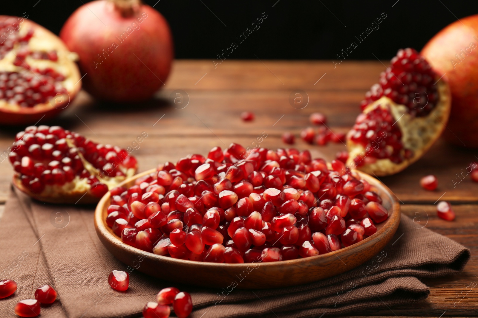 Photo of Ripe juicy pomegranates and grains on wooden table