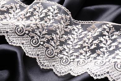 Beautiful white lace on black fabric, closeup