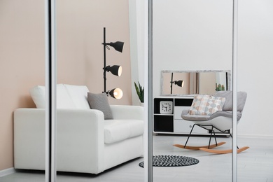 Photo of Beautiful room interior with rocking chair and sofa. Reflection in mirror