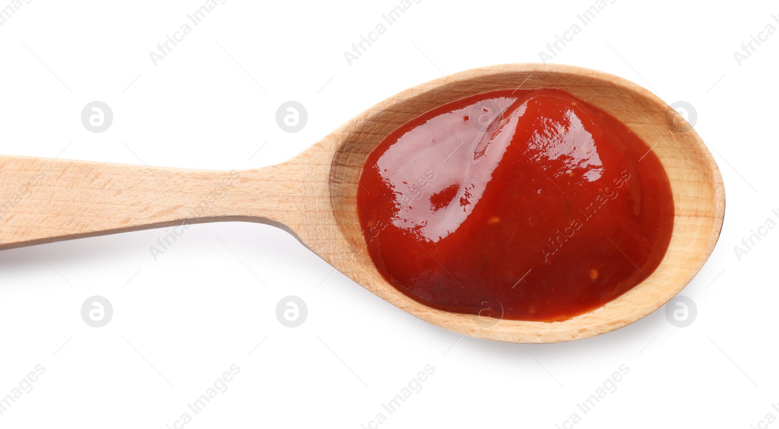 Photo of Tasty ketchup in wooden spoon isolated on white, top view