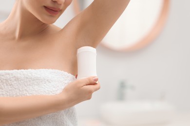 Photo of Woman applying deodorant in bathroom, closeup. Space for text