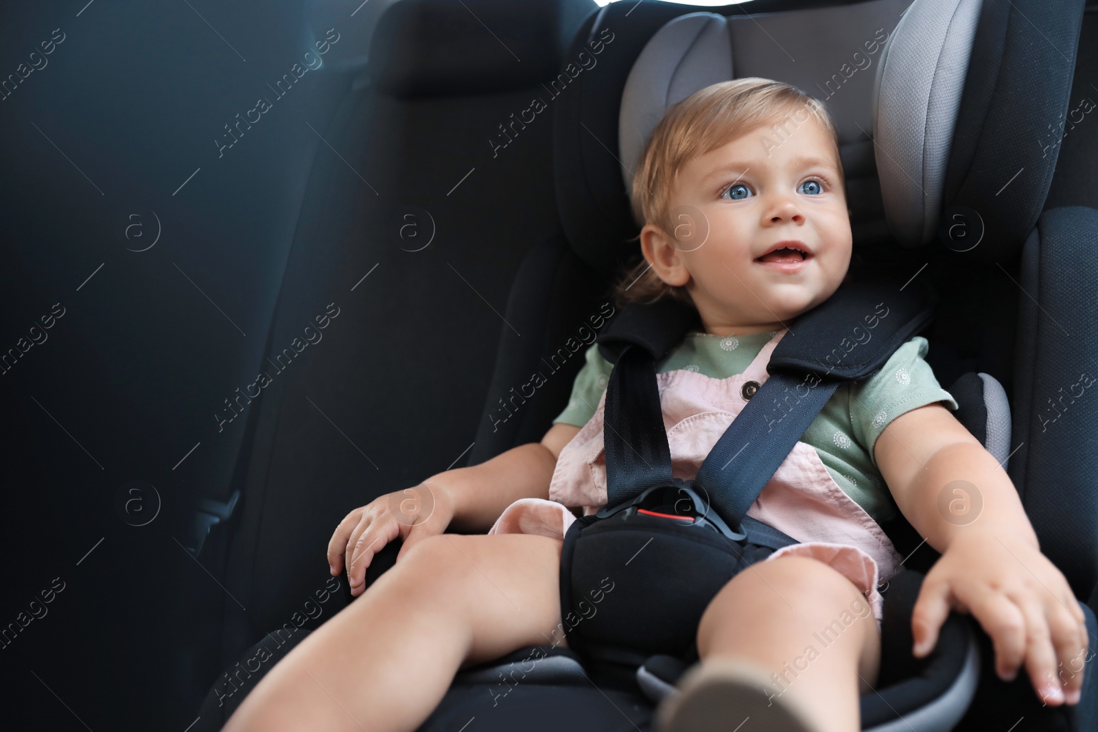 Photo of Cute little girl sitting in child safety seat inside car