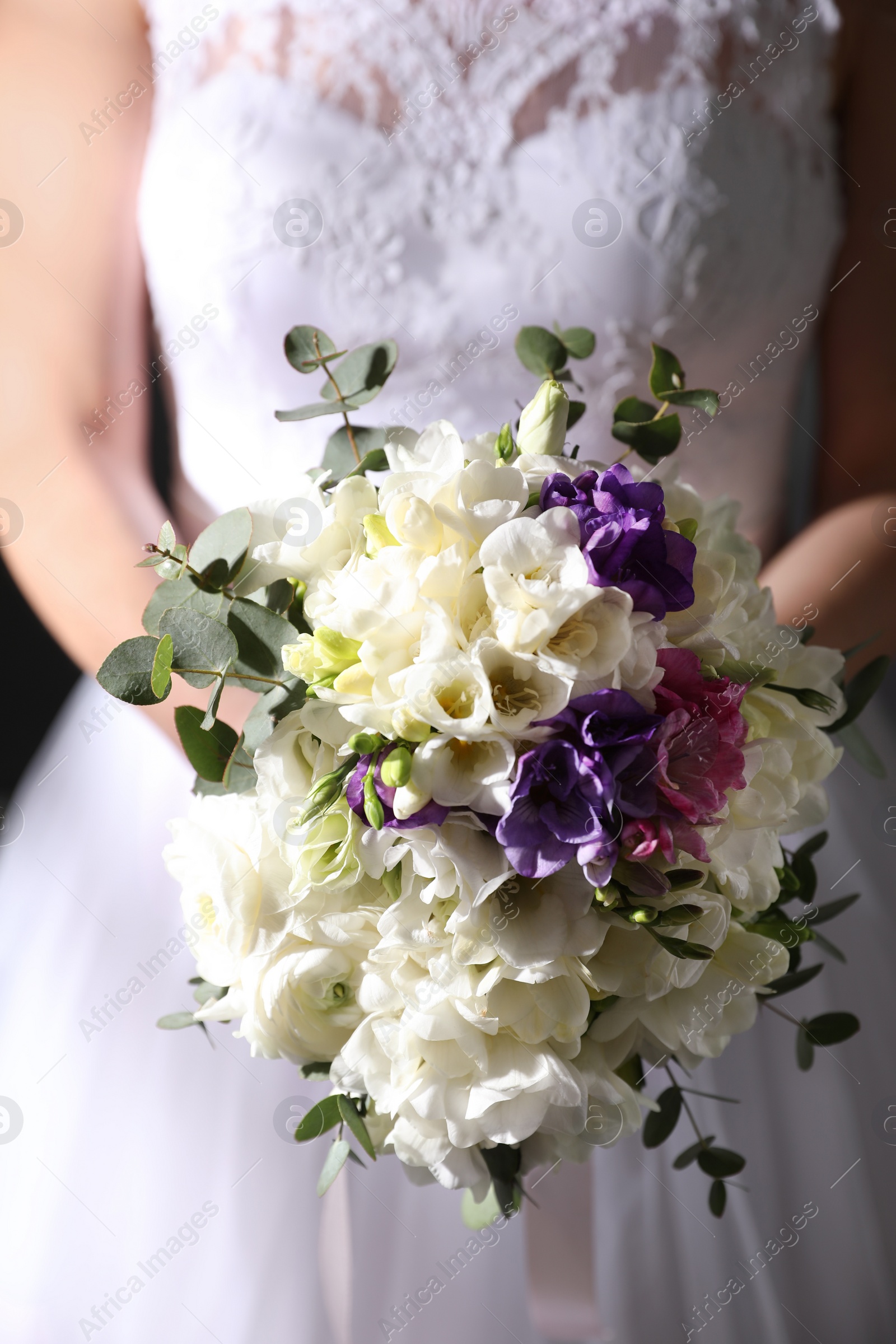 Photo of Bride holding beautiful bouquet with spring freesia flowers, closeup