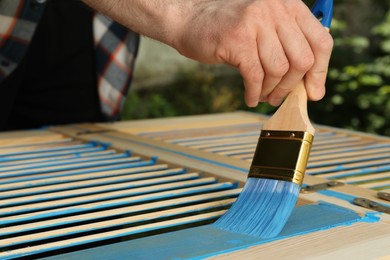 Man painting wooden surface with blue dye outdoors, closeup