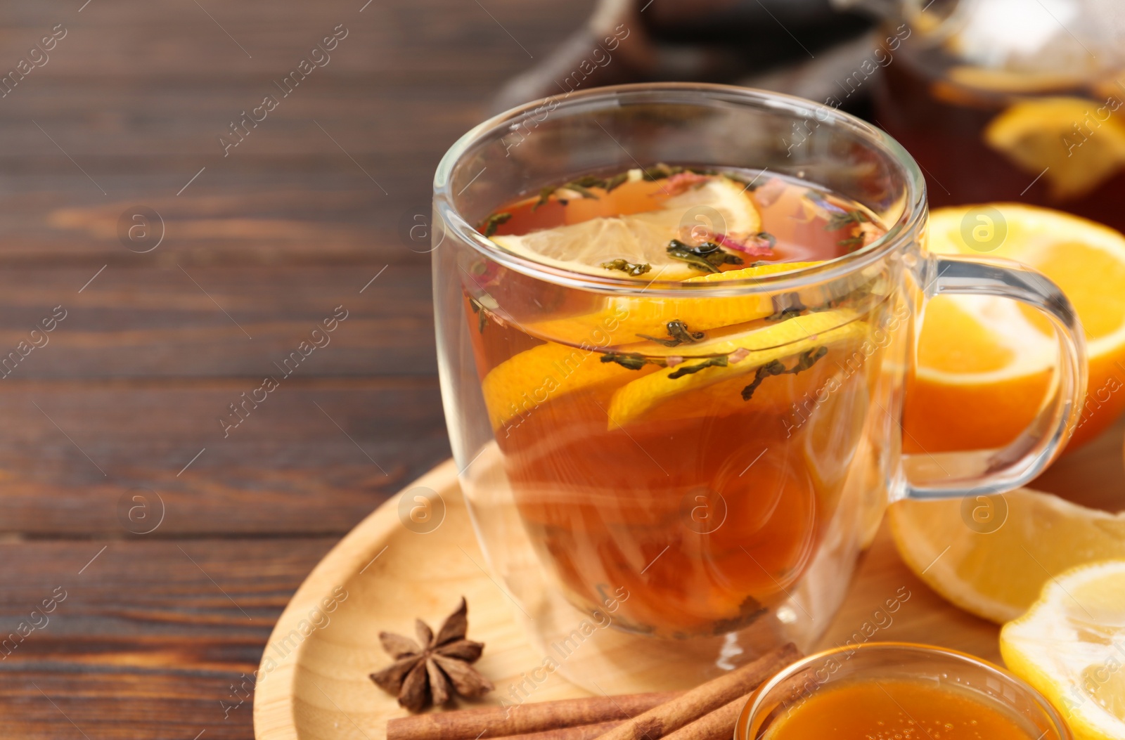 Photo of Glass cup with hot tea on wooden table, closeup