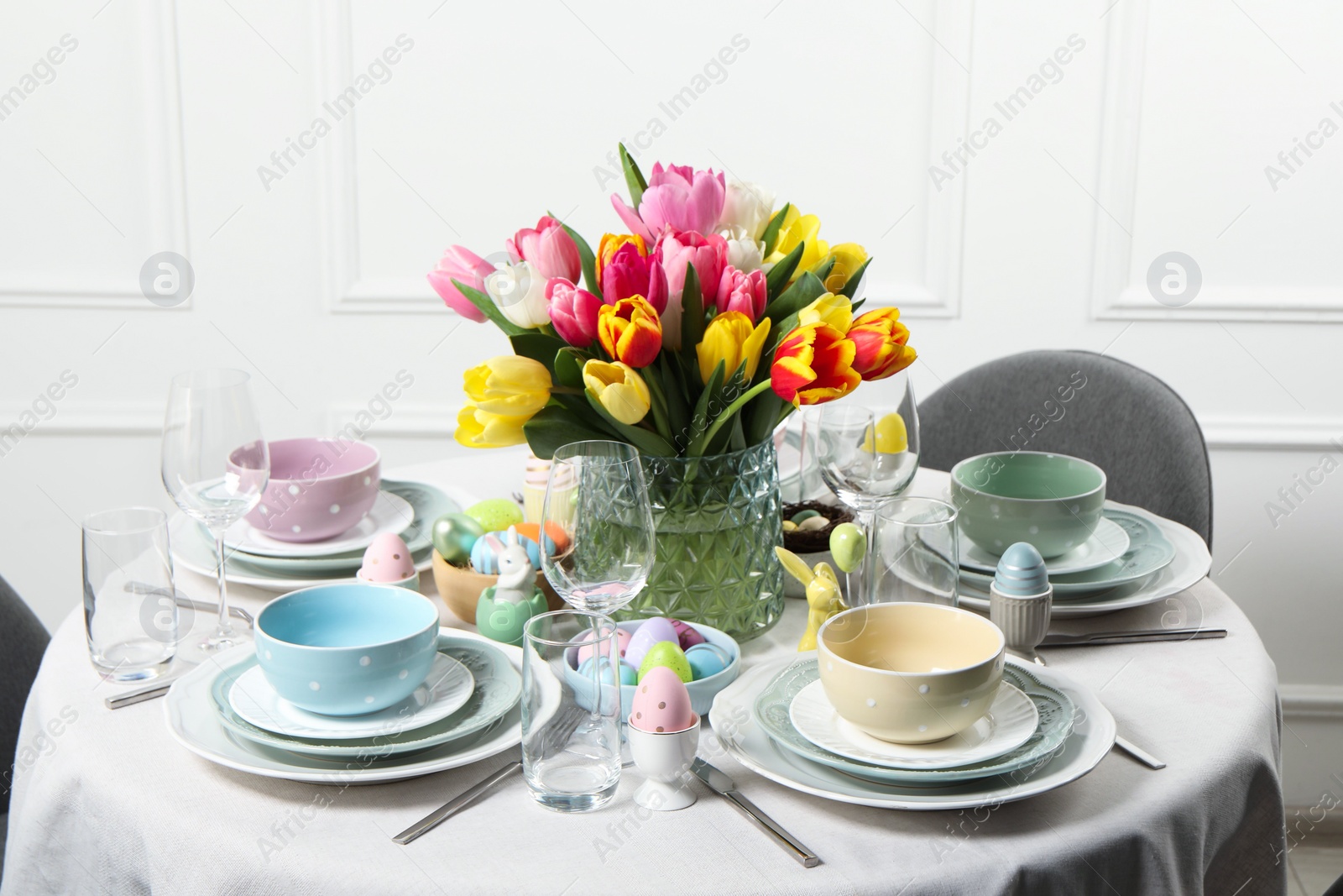 Photo of Easter celebration. Festive table setting with beautiful flowers and painted eggs