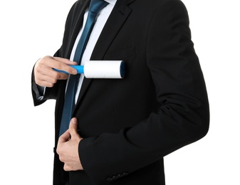 Young man cleaning jacket with lint roller on white background