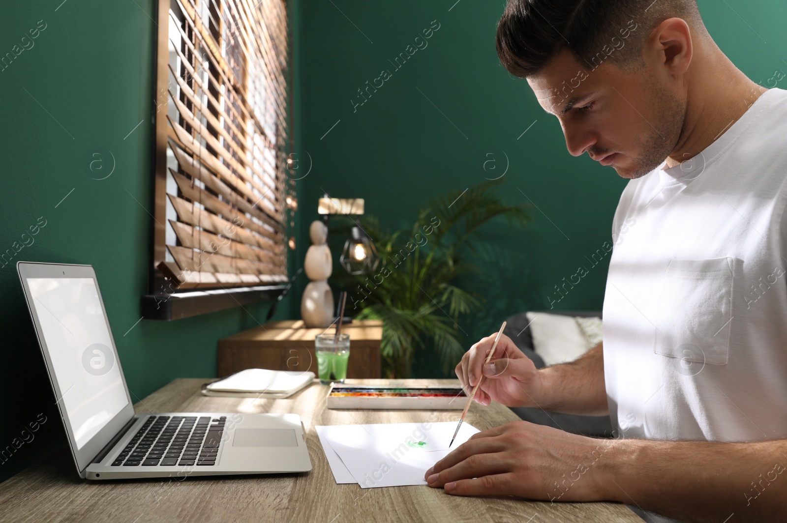 Photo of Man drawing with paints at online lesson indoors. Distance learning