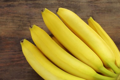 Photo of Bunch of ripe yellow bananas on wooden table, closeup