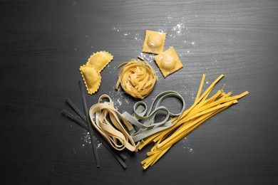 Flat lay composition with different types of pasta on black wooden table