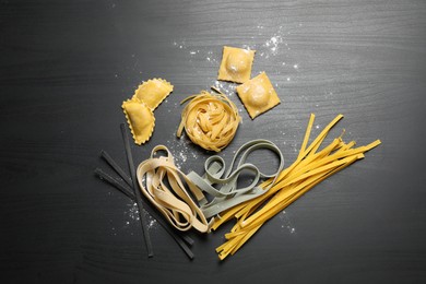 Photo of Flat lay composition with different types of pasta on black wooden table