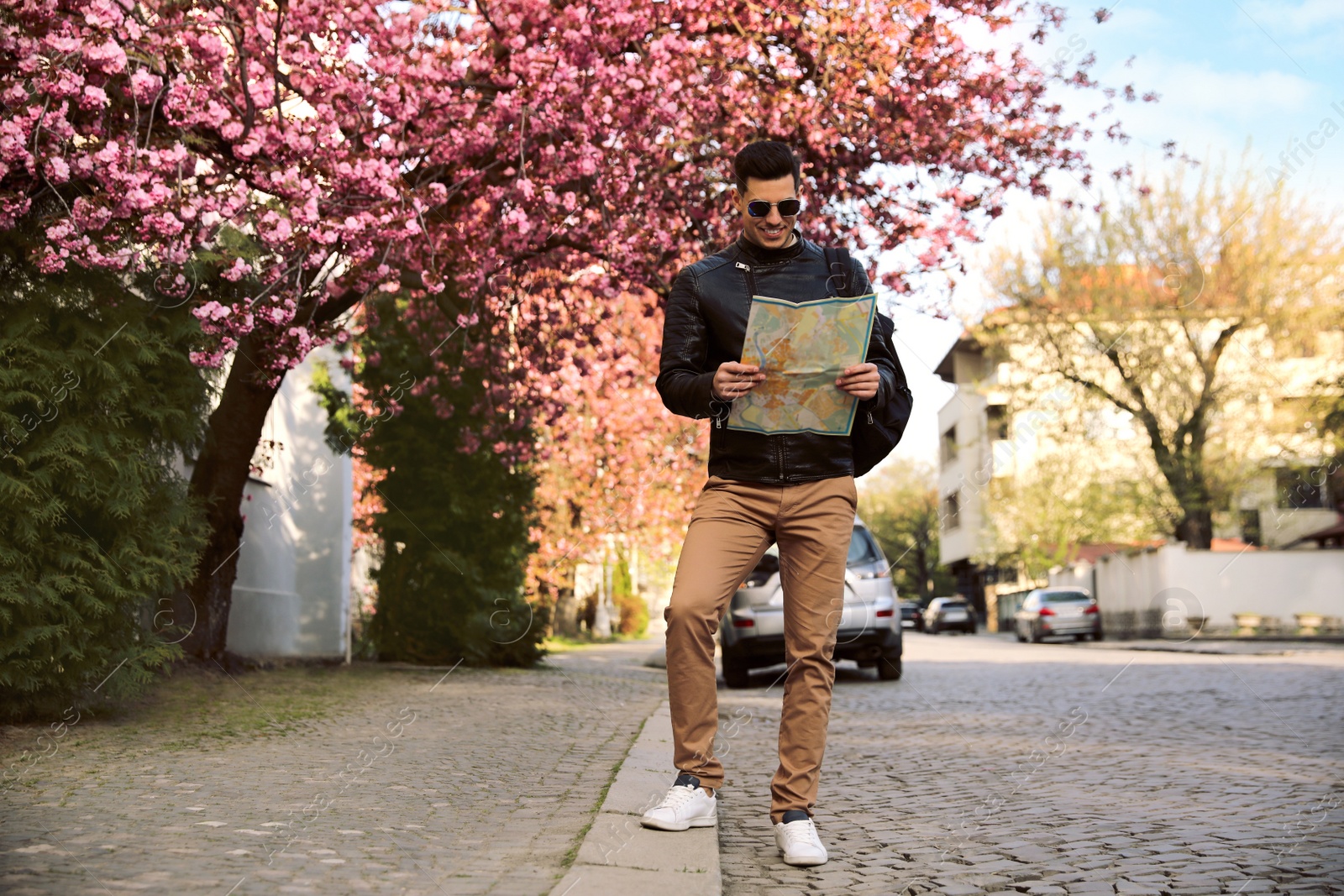 Photo of Happy male tourist with map on city street