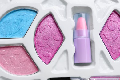 Photo of Decorative cosmetics for kids. Eye shadow palette with lipstick as background, top view