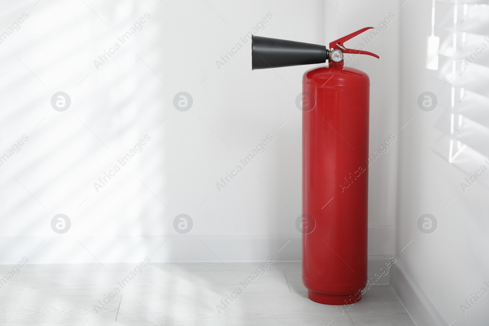 Photo of Fire extinguisher near white wall indoors. Space for text