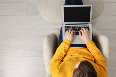 Photo of Man working with laptop in armchair, top view. Space for text