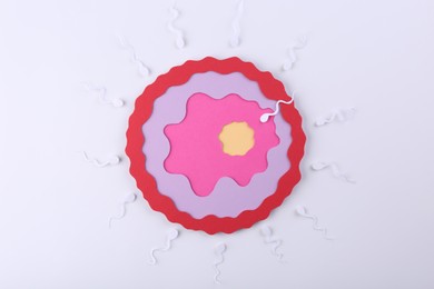 Photo of Fertilization concept. Sperm cells swimming towards egg cell on white background, top view