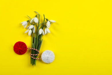 Photo of Beautiful snowdrops with traditional martisor on yellow background, flat lay and space for text. Symbol of first spring day